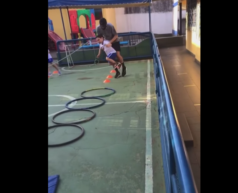 Un profesor ayuda a un alumno discapacitado a disfrutar de los ejercicios de gimnasia
